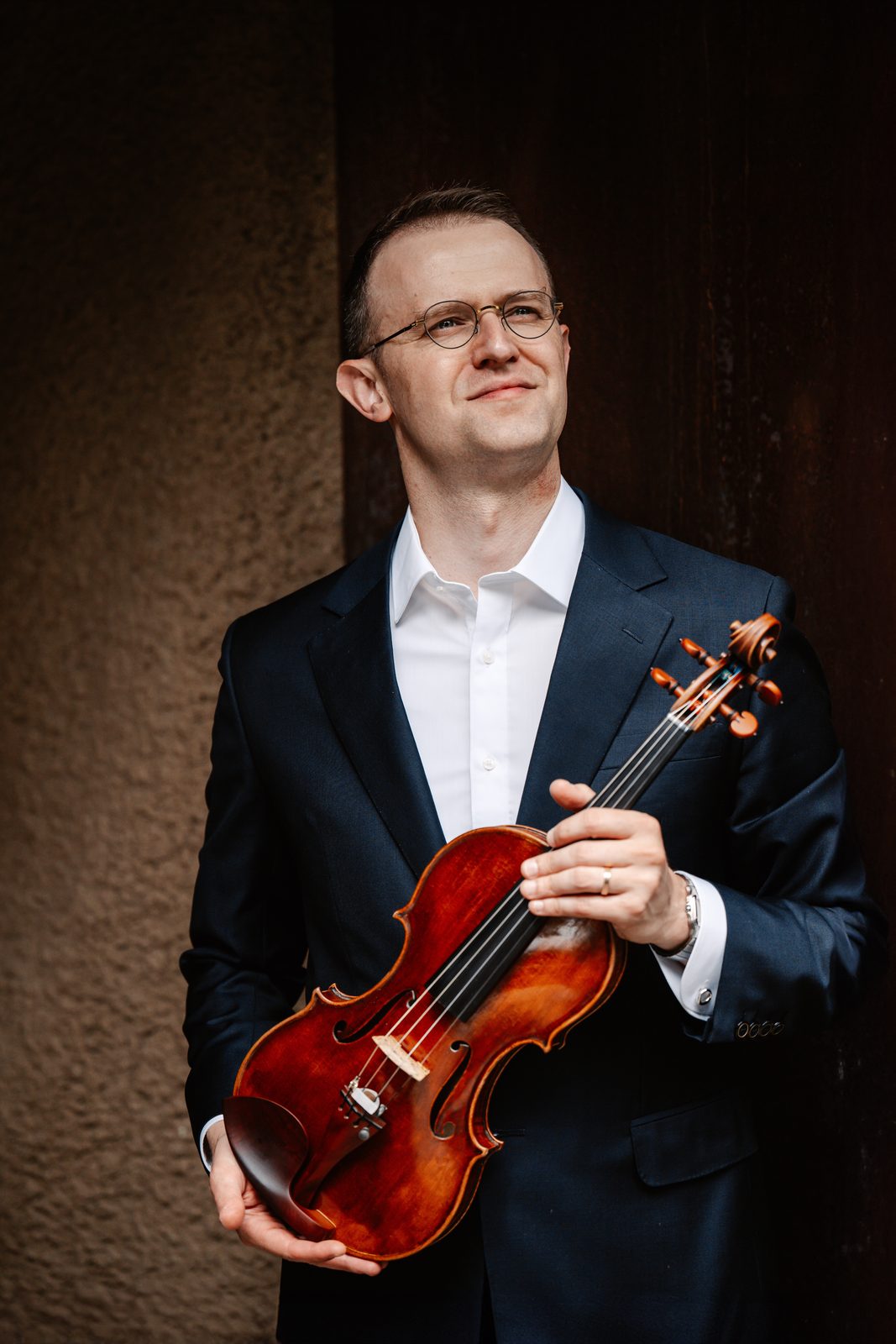 David Southorn holding his violin up, dark urban background