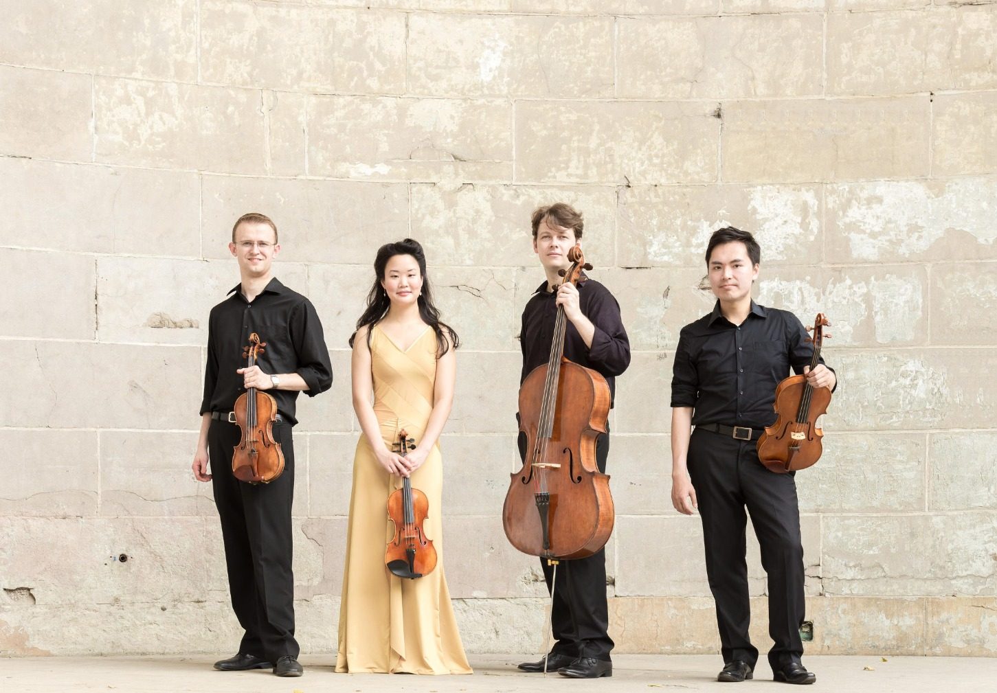 Four musicians, including David Southorn, standing against a light stone wall