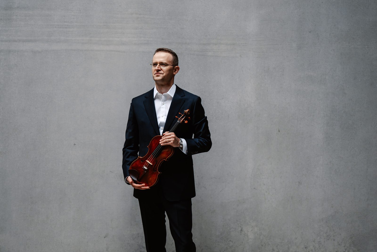 David Southorn, full-length portrait standing with violin against a grey wall